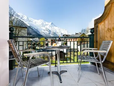 a patio with a table and chairs on a balcony with mountains at Apartment Die Sonnailles apartment by Interhome in Chamonix-Mont-Blanc