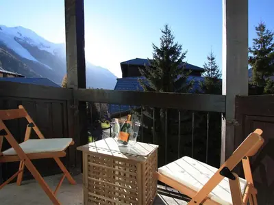 a patio with two chairs and a table with wine glasses at Apartment Rupicapra Wohnung by Interhome in Chamonix-Mont-Blanc