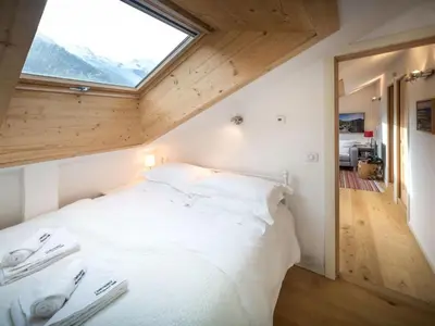 a bedroom with a white bed with a large window at Apartment Rupicapra Wohnung by Interhome in Chamonix-Mont-Blanc