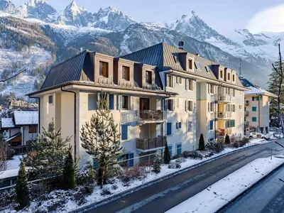 a large apartment building with mountains in the background at Apartment Angenehme Wohnung in Chamonix Centre-Ville by Interhome in Chamonix-Mont-Blanc