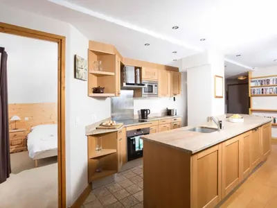 a kitchen with wooden cabinets and a kitchen island at Apartment Die Belle Epoque Wohnung by Interhome in Chamonix-Mont-Blanc