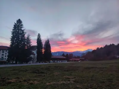 a sunset over a field with trees and a road at La Tanière des Cimes Sauna privé in Passy