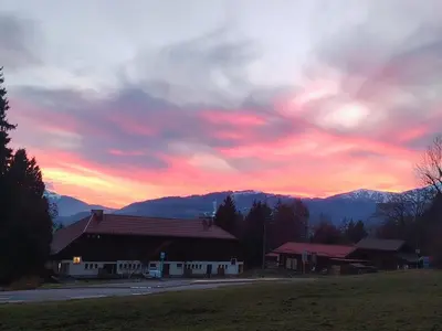 a sunset over a building with mountains in the background at La Tanière des Cimes Sauna privé in Passy