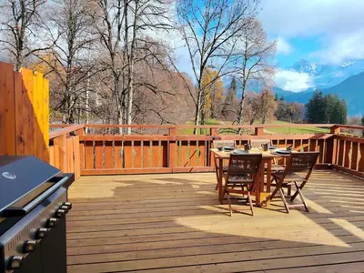 a wooden deck with a table and chairs on it at La Tanière des Cimes Sauna privé in Passy