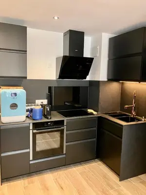 a kitchen with black cabinets and a stove top oven at Calm & Cozy Apartment with Parking in Sallanches in Sallanches