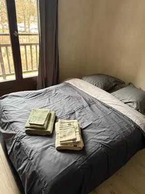 a bed with two bags on it with a window at Studio 2 personnes situation idéal a Sallanches 74400 in Sallanches