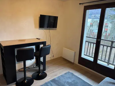 a room with a desk with two chairs and a television at Studio 2 personnes situation idéal a Sallanches 74400 in Sallanches