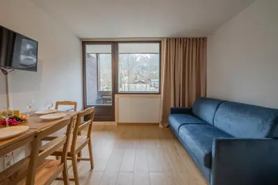 a living room with a table and a blue couch at Chamonix Sud - Grepon 104 - Happy Rentals in Chamonix-Mont-Blanc