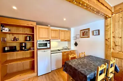 a kitchen with a table and a white refrigerator at Escape Mountain Apartment with Stunning Views in Combloux