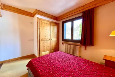 a bedroom with a red bed and a window at Escape Mountain Apartment with Stunning Views in Combloux