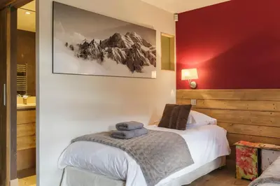 a bedroom with a bed and a red wall at Megepi Chalet 5CH Calme Remontee 400m Sauna Fitness in Demi-Quartier
