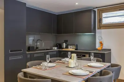 a kitchen with a table and chairs and a kitchen with black cabinets at Jacaranda 5 - Sublime 6pax - Central - Confort - Parking in Chamonix-Mont-Blanc