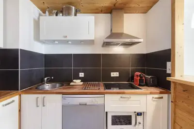 a kitchen with white cabinets and a sink at Les Choucas Spacieux 2CH Parking Calme Vues 5mn centre in Chamonix-Mont-Blanc