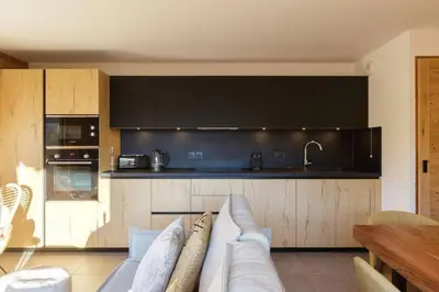 a living room with a couch and a kitchen at Terra Losa AlpinChic 2CH Central Remontee Vue Parking in Les Houches