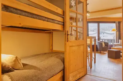 a bedroom with a bunk bed and a living room at La Verte Appart 2CH familial 5mn pistes Vue Parking in Les Houches