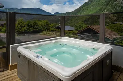 a jacuzzi tub on a balcony with a view at Grosse Pierre Chalet 180m2 Cheminee Jacuzzi Vue Taconnaz in Les Houches