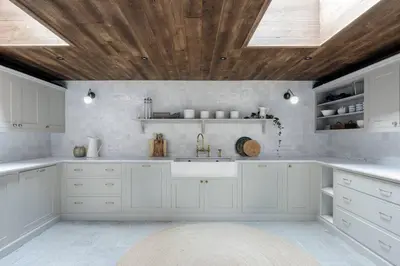 a kitchen with white cabinets and a wooden ceiling at Peter Pan Chalet Luxe Sauna Jacuzzi Cinema Vue 180 in Les Houches