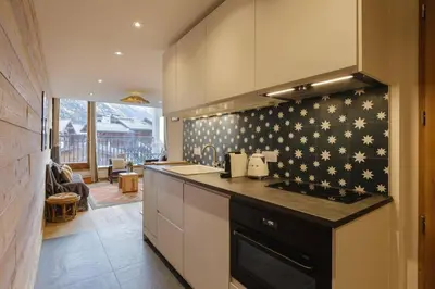 a kitchen with a stove top oven next to a living room at Vallee Blanche Central 4pax Vue MtBlanc Parking 400m Remontee in Chamonix-Mont-Blanc