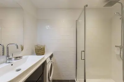 a white bathroom with a shower and a sink at Vallee Blanche Central 4pax Vue MtBlanc Parking 400m Remontee in Chamonix-Mont-Blanc