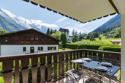 a table on a balcony with a view of a mountain at Closy Modern 4pax Pied Piste Centre Balcon Parking in Chamonix-Mont-Blanc
