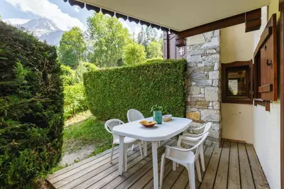 a white table and chairs on a wooden deck at Chavants Apart 3CH Famille Pied Piste Piscine Parking in Les Houches