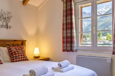 a bedroom with a bed and a window with mountains at Moulin - Ultra Central T2 - Vue Mt Blanc - Quartier Vivant in Chamonix-Mont-Blanc