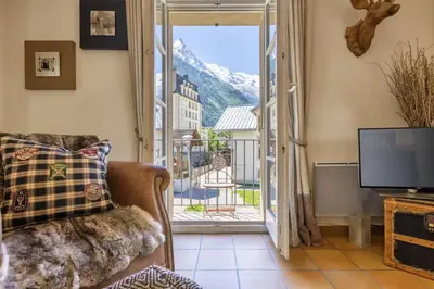 a living room with a couch and a television and a balcony at Moulin - Ultra Central T2 - Vue Mt Blanc - Quartier Vivant in Chamonix-Mont-Blanc
