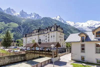 a large building with mountains in the background at Moulin - Ultra Central T2 - Vue Mt Blanc - Quartier Vivant in Chamonix-Mont-Blanc