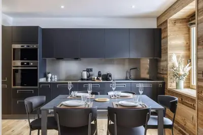 a kitchen with black cabinets and a table and chairs at Ocma 4 Somptueux 6pax Central Parking Confort in Chamonix-Mont-Blanc