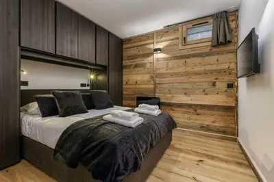 a bedroom with a bed and a wooden wall at Ocma1 Somptueux 6pax Central Parking Confort in Chamonix-Mont-Blanc