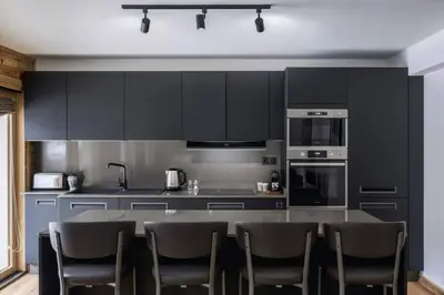 a kitchen with black cabinets and a table with chairs at Ocma1 Somptueux 6pax Central Parking Confort in Chamonix-Mont-Blanc