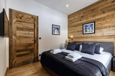 a bedroom with a large bed with a wooden wall at Ocma3 Somptueux 6pax VueMtBlanc Central Parking in Chamonix-Mont-Blanc