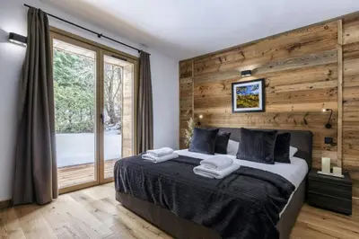 a bedroom with a large bed with wooden walls and a window at Ocma2 Somptueux 6pax VueMtBlanc Central Parking in Chamonix-Mont-Blanc