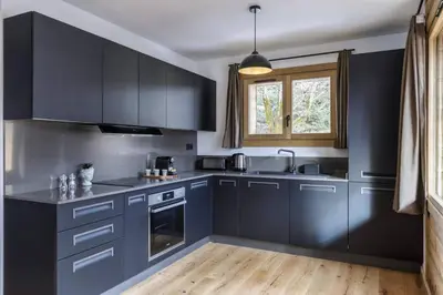 a kitchen with dark blue cabinets and a window at Ocma2 Somptueux 6pax VueMtBlanc Central Parking in Chamonix-Mont-Blanc