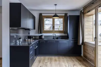a kitchen with dark blue cabinets and a window at Ocma2 Somptueux 6pax VueMtBlanc Central Parking in Chamonix-Mont-Blanc