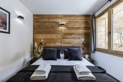 a bedroom with a large bed with a wooden wall at Ocma2 Somptueux 6pax VueMtBlanc Central Parking in Chamonix-Mont-Blanc