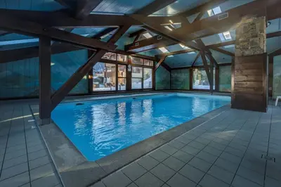 a large swimming pool with a wooden ceiling at Verny Appart 2CH Familiale Pied Pistes Piscine Vue in Les Houches