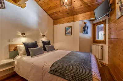 a bedroom with a large bed with a tv on the wall at Verny Appart 2CH Familiale Pied Pistes Piscine Vue in Les Houches