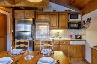 a kitchen with a wooden table with glasses on it at Verny Appart 2CH Familiale Pied Pistes Piscine Vue in Les Houches