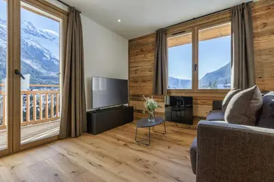 a living room with a couch and a television and mountains at Jacaranda2 Sublime 6pax Vue MtBlanc Central Parking in Chamonix-Mont-Blanc