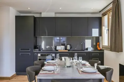 a kitchen with a table with chairs and a kitchen with black cabinets at Jacaranda2 Sublime 6pax Vue MtBlanc Central Parking in Chamonix-Mont-Blanc