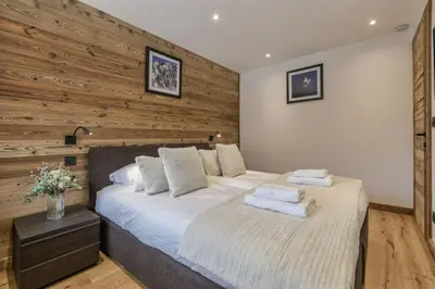 a bedroom with a large bed with a wooden wall at Jacaranda1 Sublime 8pax 100m2 Vue MtBlanc Central Parking in Chamonix-Mont-Blanc