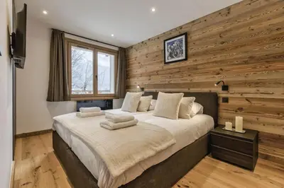 a bedroom with a large bed with a wooden wall at Jacaranda1 Sublime 8pax 100m2 Vue MtBlanc Central Parking in Chamonix-Mont-Blanc