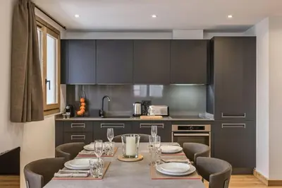 a kitchen with a long table with chairs and a kitchen with black cabinets at Jacaranda3 Sublime 6pax Vue MtBlanc Central Parking in Chamonix-Mont-Blanc