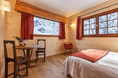 a bedroom with a bed and a table and window at La Loriaz Chalet 7pax Nature Le Planet 5mn Argentiere in Chamonix-Mont-Blanc