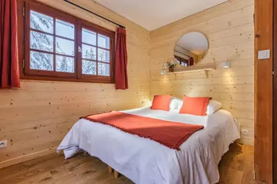a bedroom with wooden walls and a bed with red pillows at La Loriaz Chalet 7pax Nature Le Planet 5mn Argentiere in Chamonix-Mont-Blanc