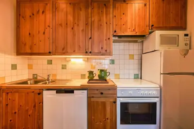 a kitchen with wooden cabinets and a white refrigerator at La Loriaz Chalet 7pax Nature Le Planet 5mn Argentiere in Chamonix-Mont-Blanc