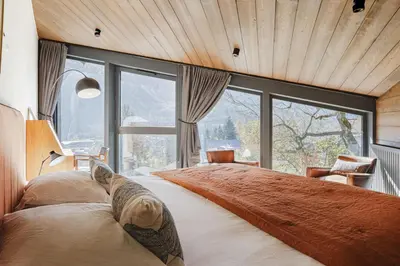 a bedroom with a large bed with a large window at Le Murger Chalet de Luxe 240m2 6 CH Vue MtBlanc Sauna in Chamonix-Mont-Blanc
