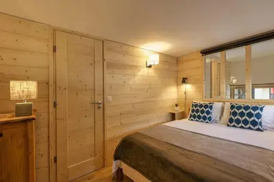 a bedroom with a bed with wooden walls and a window at Roca Cosy Duplex Grands Montets Parking Transports in Chamonix-Mont-Blanc