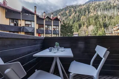 a white table and chairs on a balcony with a building at Roca Cosy Duplex Grands Montets Parking Transports in Chamonix-Mont-Blanc